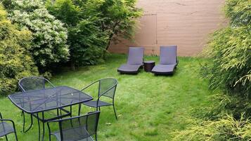 Un espace patio aménagé avec une table et des chaises, deux fauteuils de relaxation et une petite table ronde.