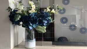 Una mesa de recepción con un jarrón de flores y placas decorativas azules en la pared.