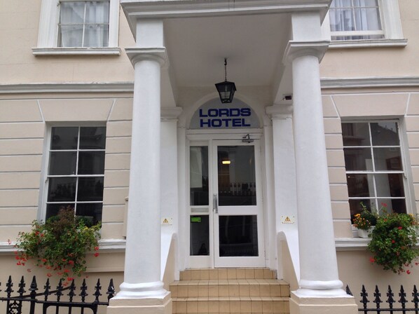 The front entrance of the Lords Hotel with a classic architectural design, including white columns and a sign above the door. - Lords Hotel (London)