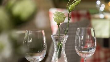 A dining table with three wine glasses and a vase with a flower.