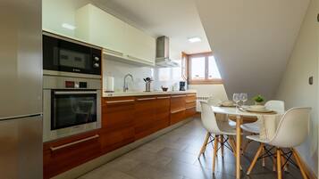 A modern kitchen with a dining area, featuring a Bosch oven, white cabinets, and a dining table with chairs.
