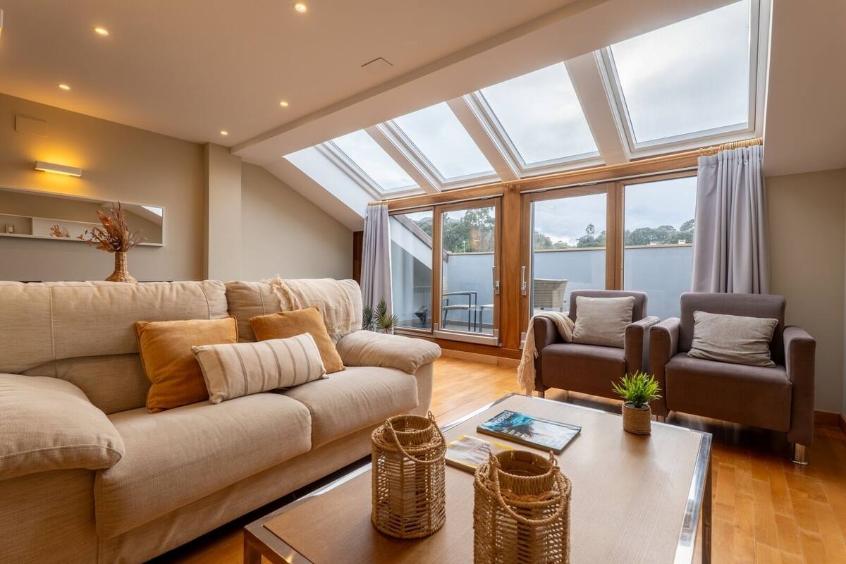 A spacious living room with a high ceiling, large windows, and a view of the outdoors.
