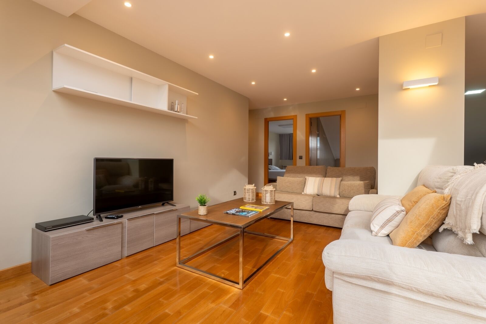 Una sala de estar moderna con un televisor de pantalla plana, una mesa de centro y un sofá.