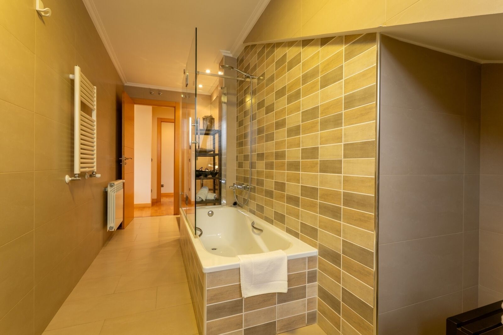 A modern bathroom with a freestanding bathtub, a glass shower enclosure, and a tiled wall.