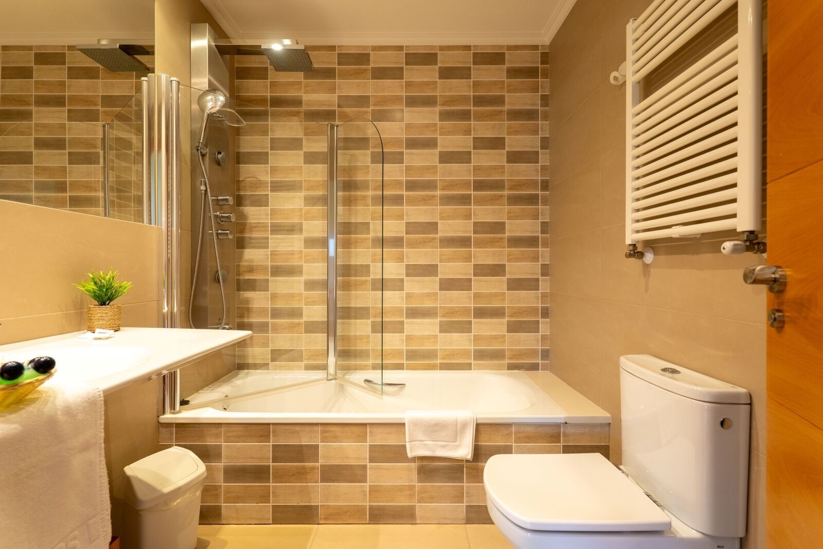 Un baño moderno con ducha de vidrio, bañera y retrete.