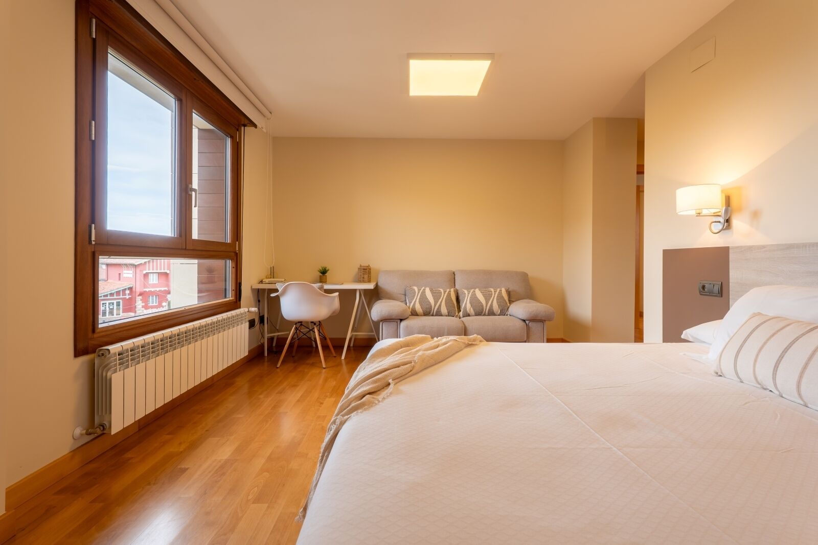 Ein Hotelzimmer mit Bett, Sofa, Schreibtisch und Fenster.