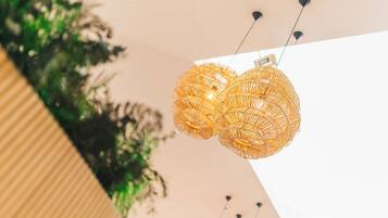 A modern interior with a unique woven light fixture and a plant in the background.