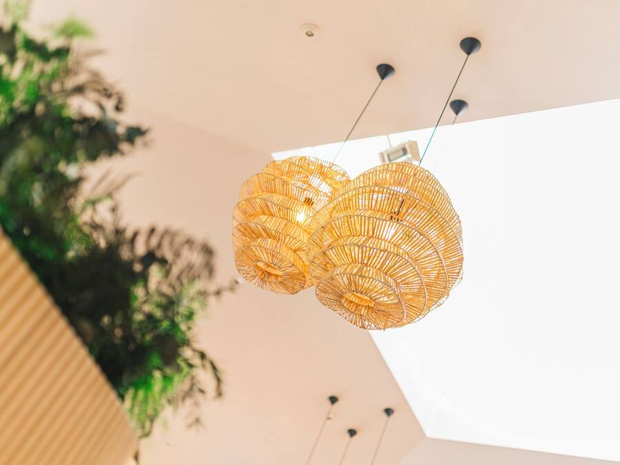 A modern interior with a unique woven light fixture and a plant in the background.