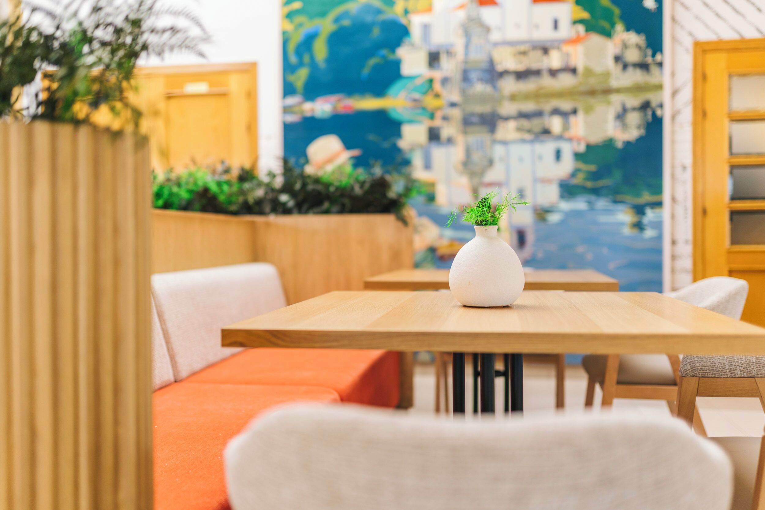 Un comedor moderno con mesas de madera y asientos con cojines naranja.