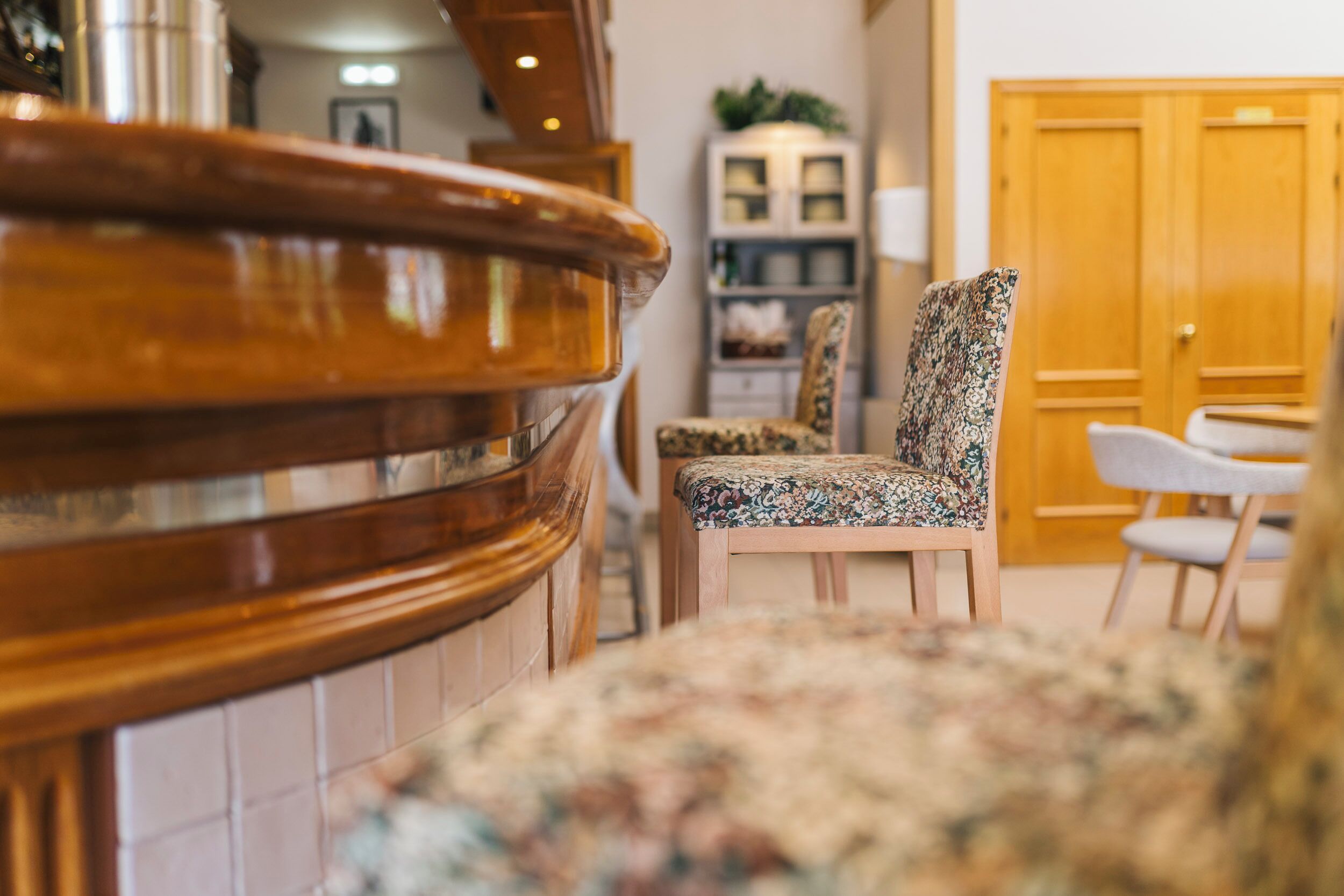 A wooden reception desk, a patterned armchair, and a wooden door in a lobby area.
