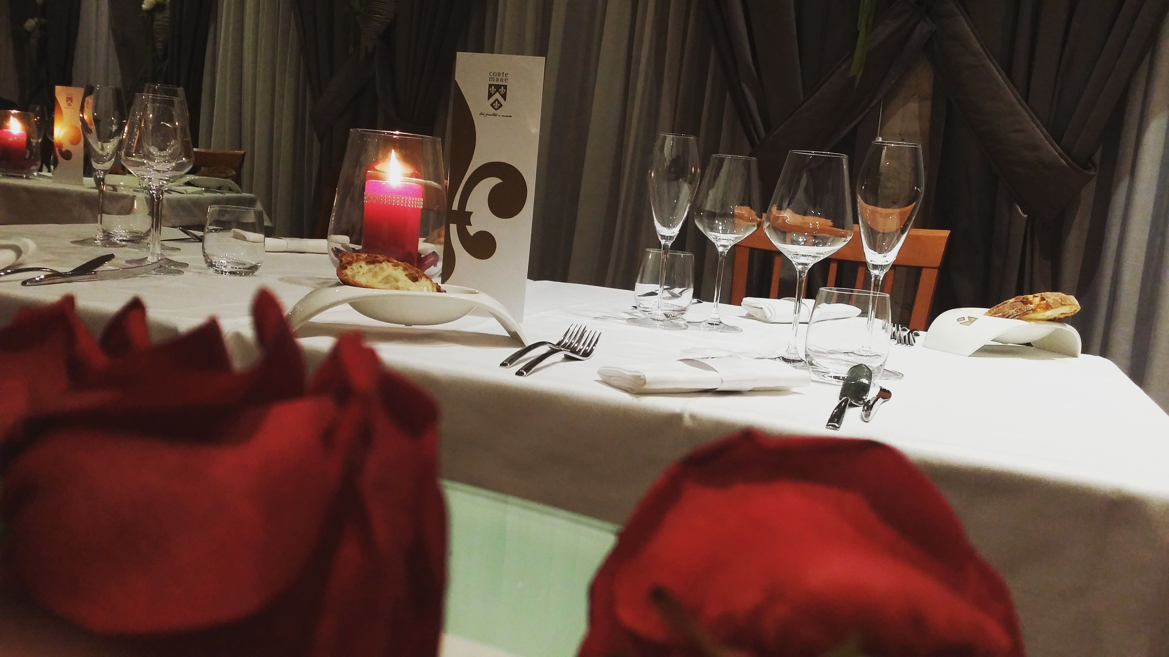 A table set for dining with a candle, glasses, and cutlery.