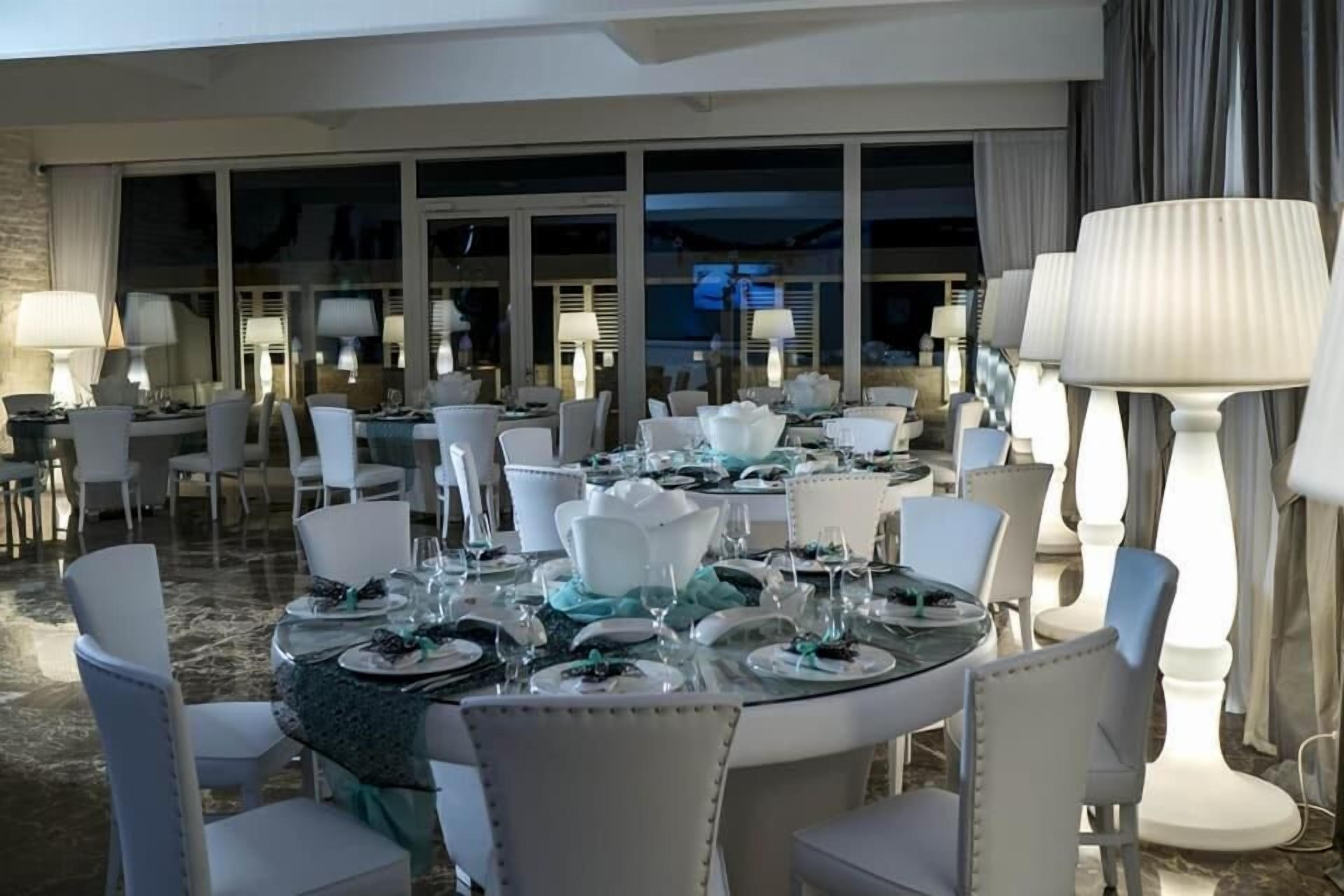 A dining area with round tables set for a meal, surrounded by chairs.
