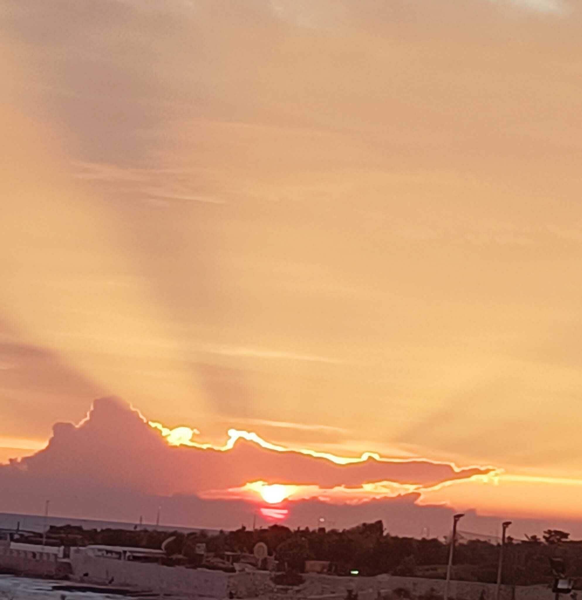 Atardecer sobre una zona costera con edificios y cielo despejado.