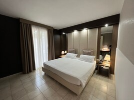 Una habitación de hotel moderna con una cama grande, lámparas de noche, una mesita de noche y un espejo.