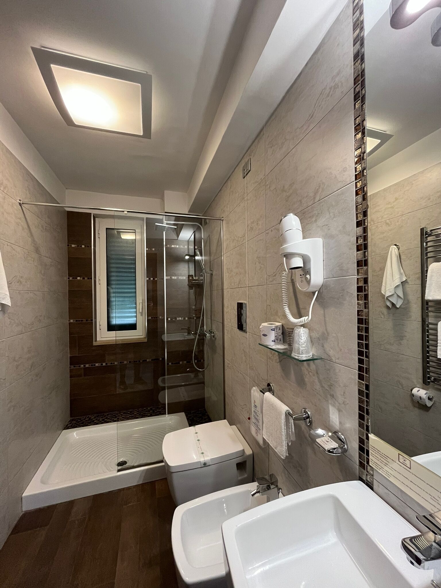 Une salle de bain moderne dotée d’une douche à parois de verre, de toilettes et de deux lavabos.