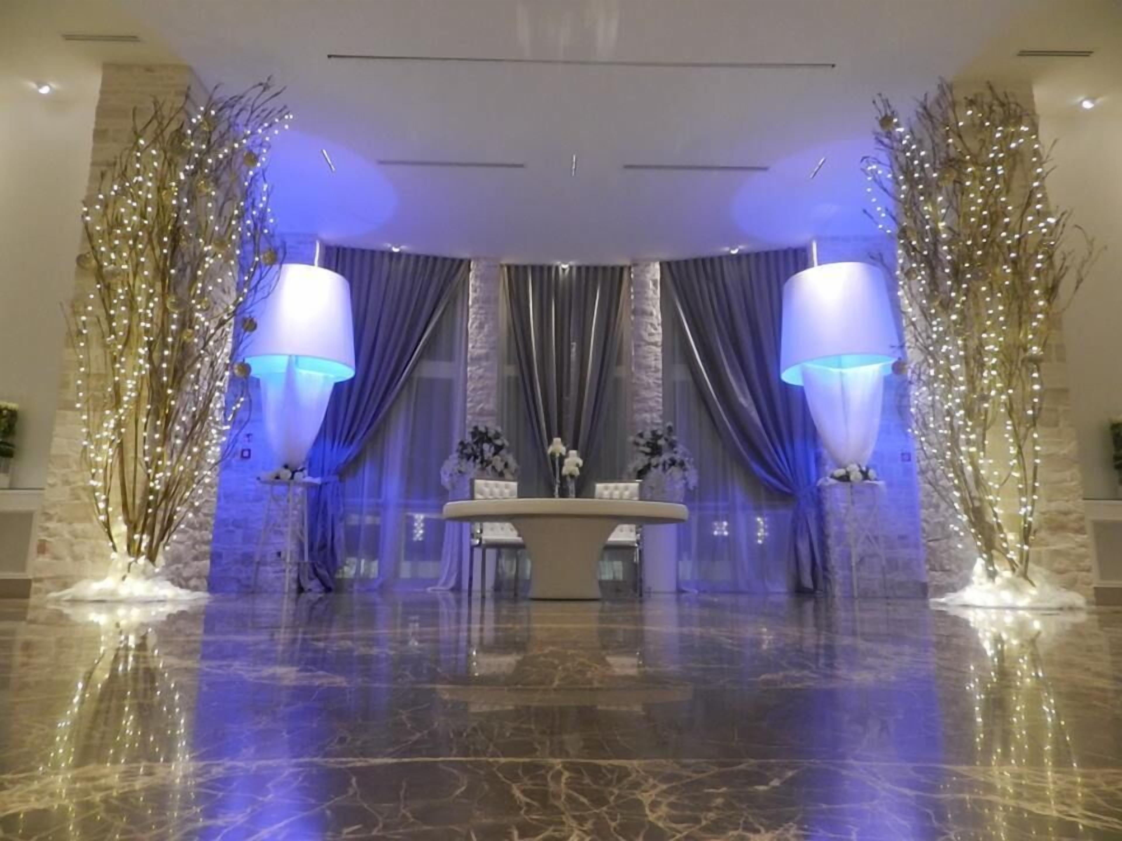 Um hall com piso de mármore, balcão de recepção e iluminação decorativa.