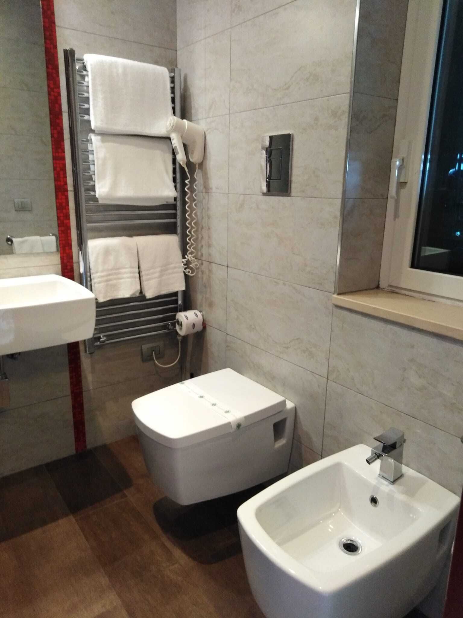 Een moderne badkamer met een wastafel, toiletgondel en handdoekhouder.