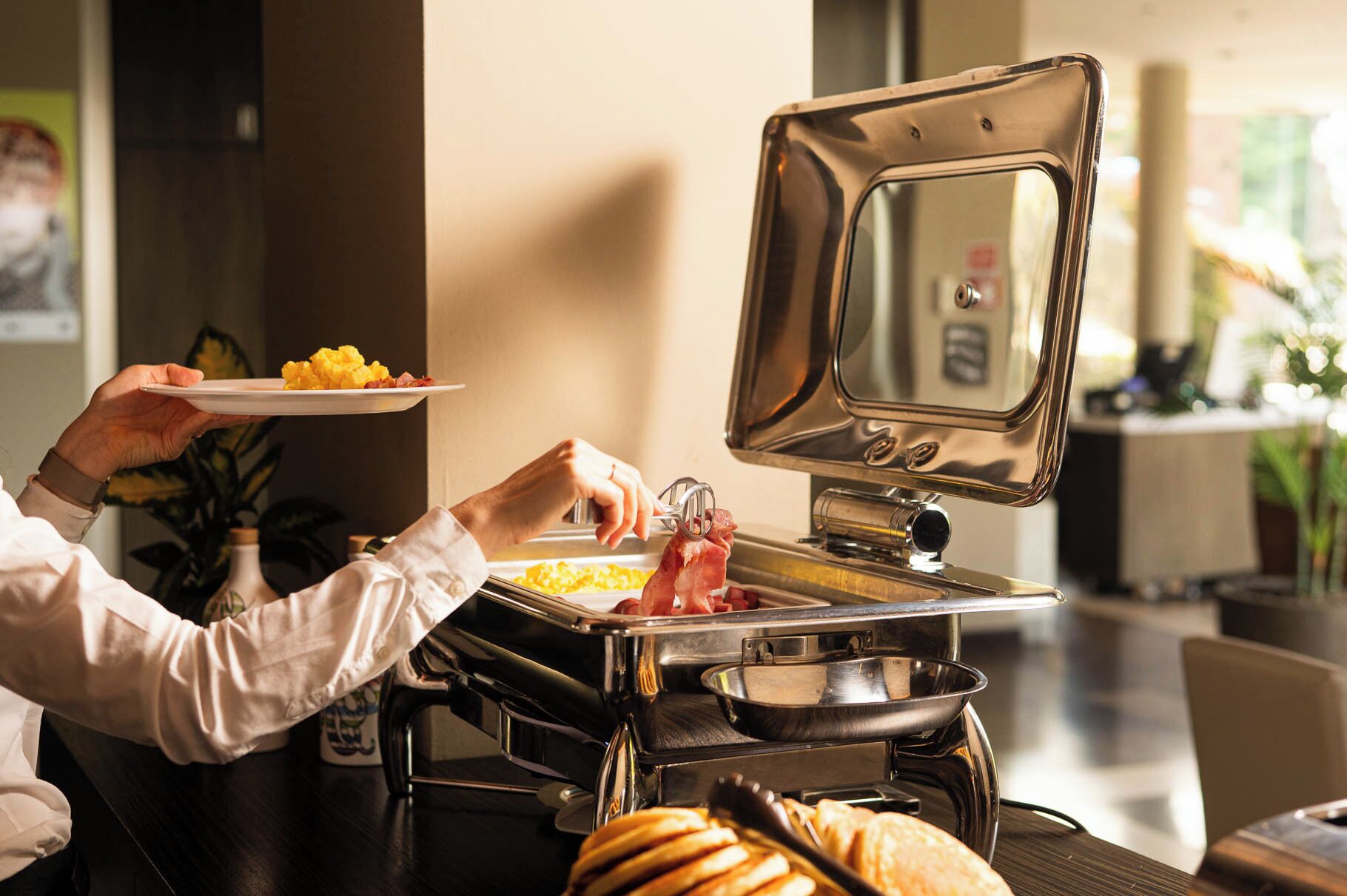 A buffet setup with a variety of food items and a person serving themselves.