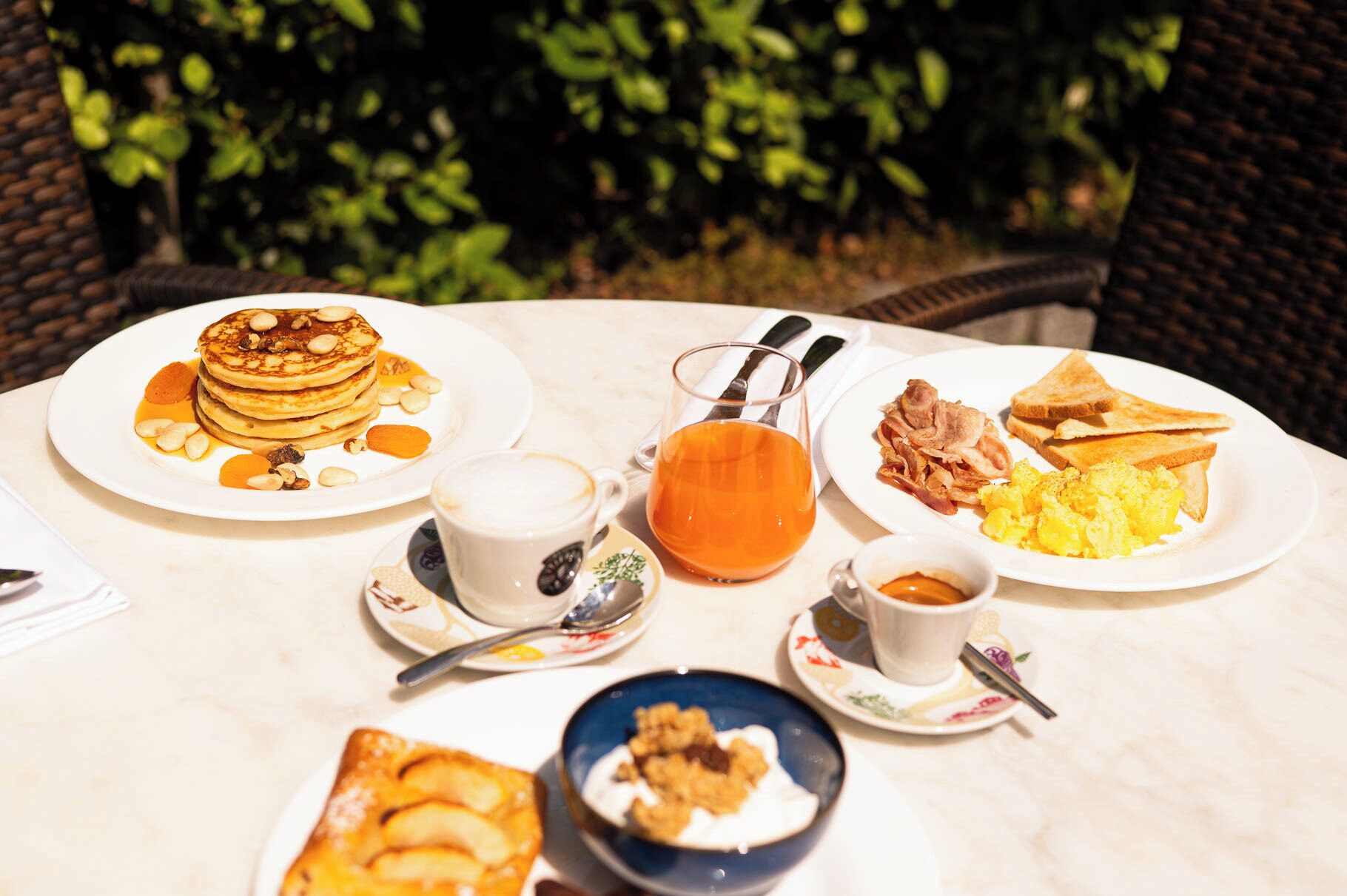 A breakfast table with pancakes, toast, scrambled eggs, and juice.