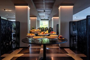 A buffet table with various desserts and fruits in a modern hotel corridor.