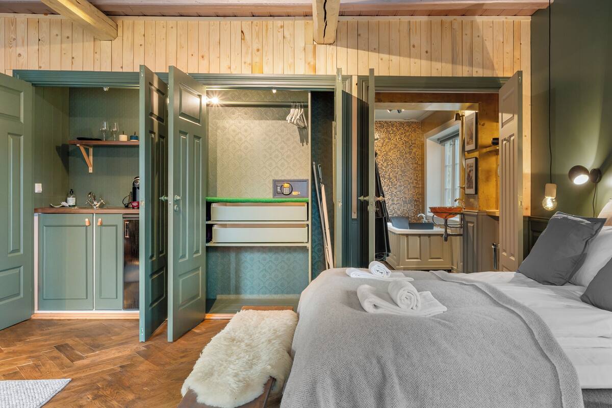 Ein Schlafzimmer mit einem Bett, einem weißen, flauschigen Teppich und einem Badezimmer mit Waschbecken und Spiegel.