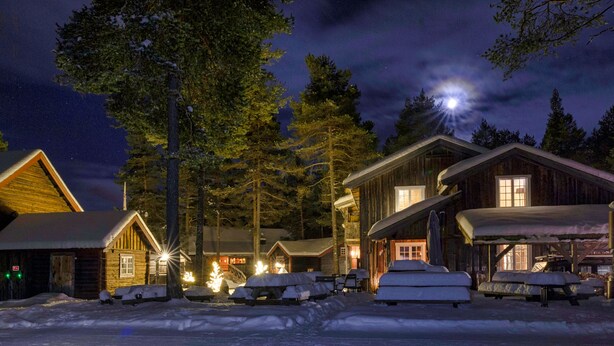 A log cabin hotel with multiple buildings, snow-covered ground, and a night sky with visible stars. - Herangtunet Mountain Lodge Norway (Øystre Slidre)