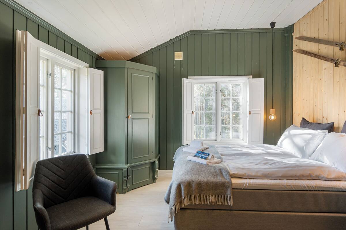 Ein Zimmer mit einem Bett, einem Sessel und einem großen Fenster.