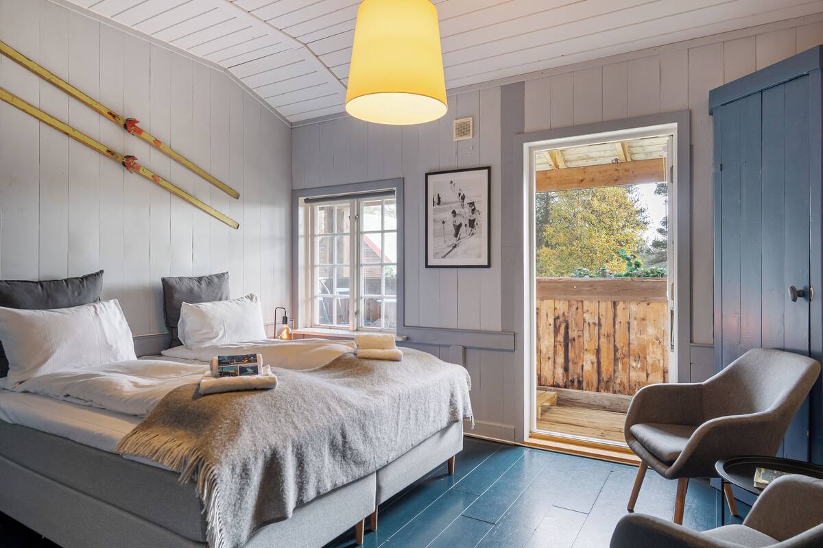 Ein Schlafzimmer mit Bett, Nachttischen, einem Fenster und Blick ins Freie.