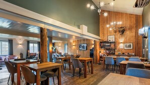 A cozy restaurant with wooden tables and chairs, a bar area, and a mounted deer head on the wall. - Herangtunet Mountain Lodge Norway (Øystre Slidre)