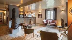 A cozy living room with a fireplace, comfortable seating, and a rustic kitchen area. - Herangtunet Mountain Lodge Norway (Øystre Slidre)