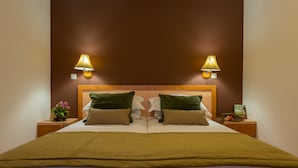 A double bed with a brown headboard, two bedside lamps, and a green book on the nightstand. - Apartments Lapad (Dubrovnik)
