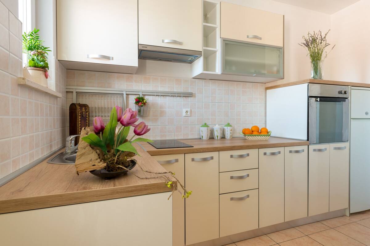Una cocina moderna con armarios blancos, encimera de madera y horno empotrado.