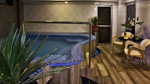 Um banheiro moderno com piso de madeira, uma pequena piscina e um espaço de estar com cadeiras e uma mesa.