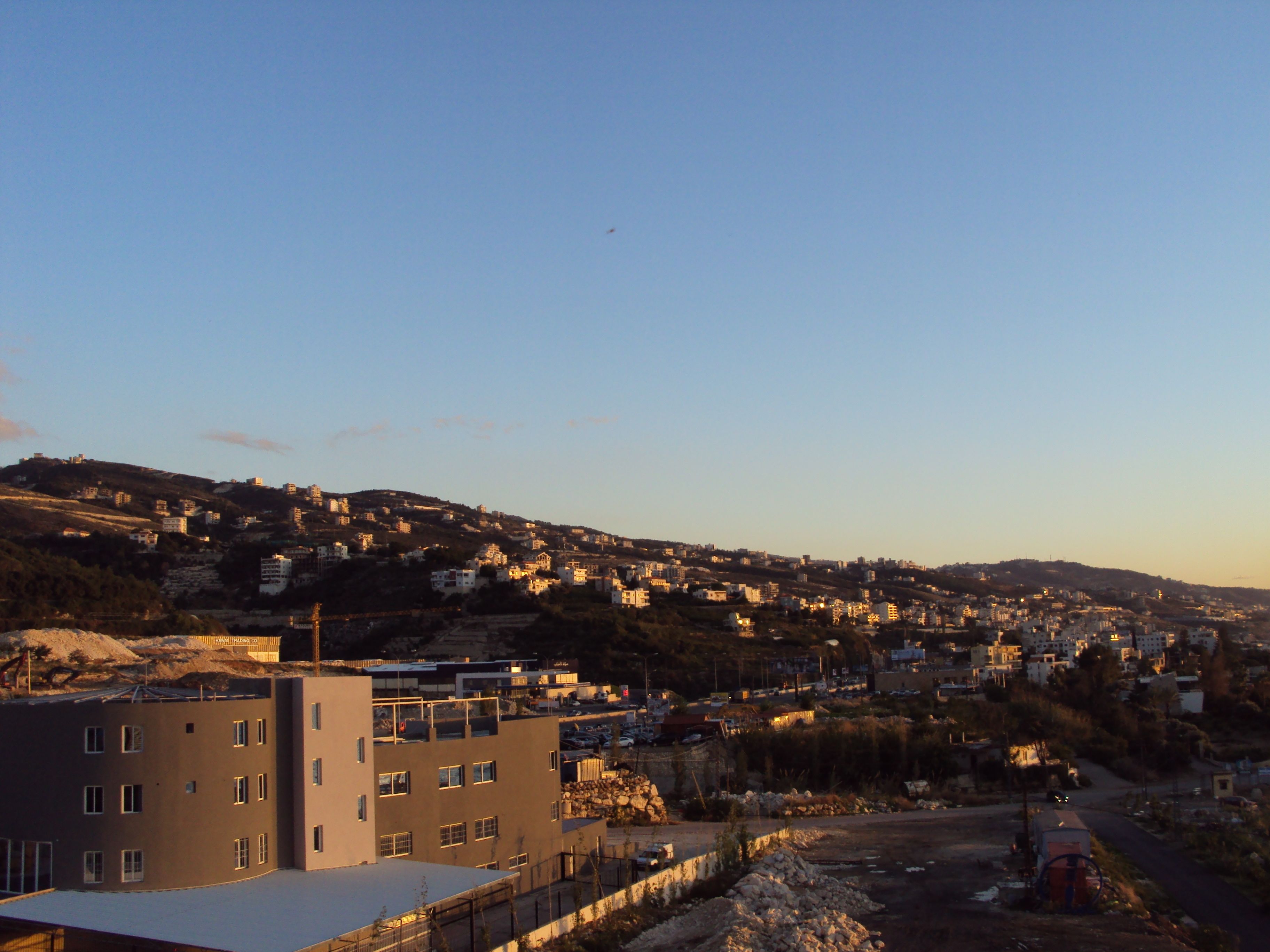 Zona residencial con edificios en una ladera, un sitio de construcción y cielo despejado.