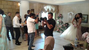 A wedding reception with a photographer taking pictures, guests standing around, and a bride in a white dress.