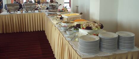 A buffet setup with multiple food stations and stacked plates.