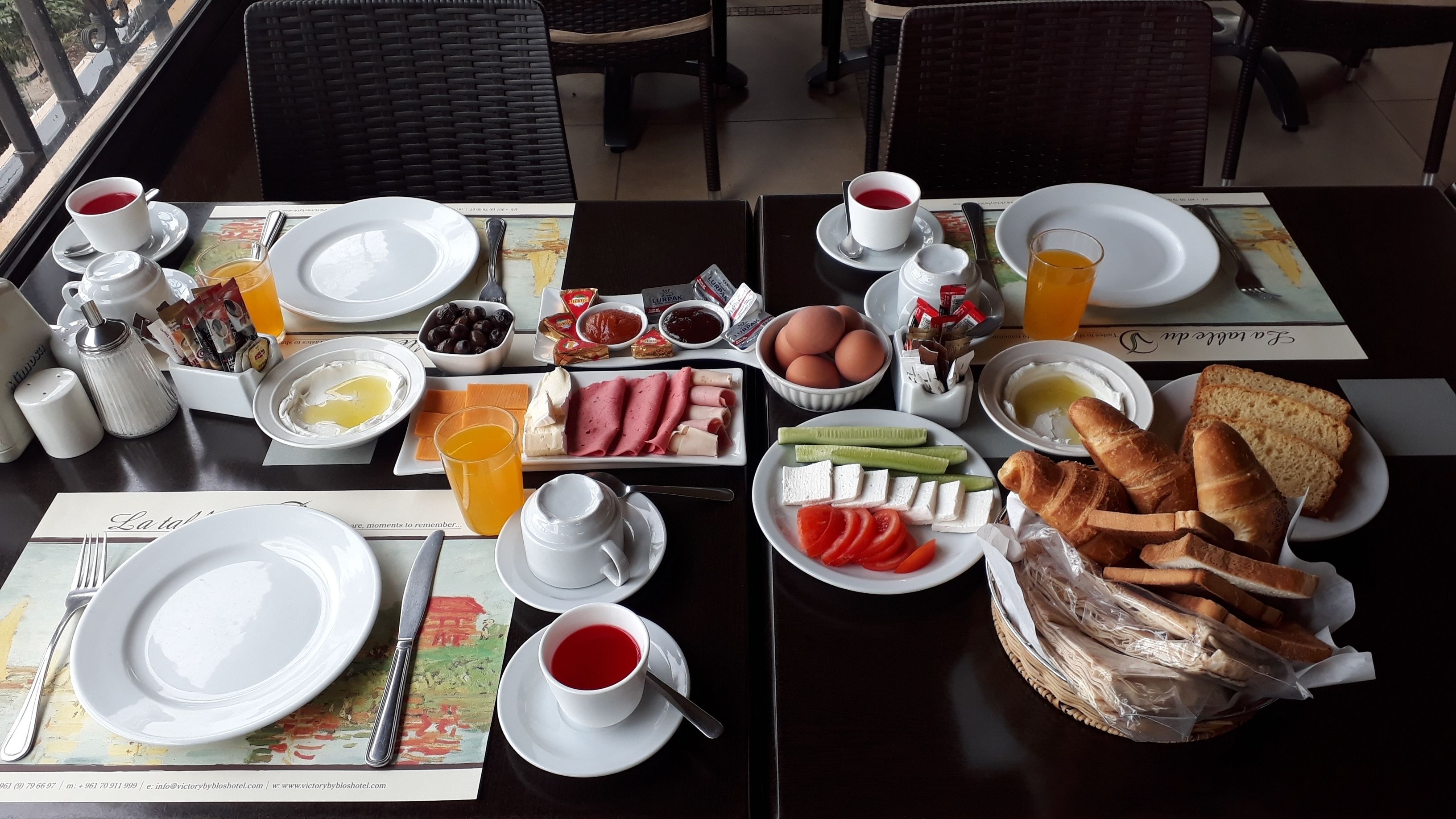 A breakfast buffet with various food items, utensils, and a view of the outside.