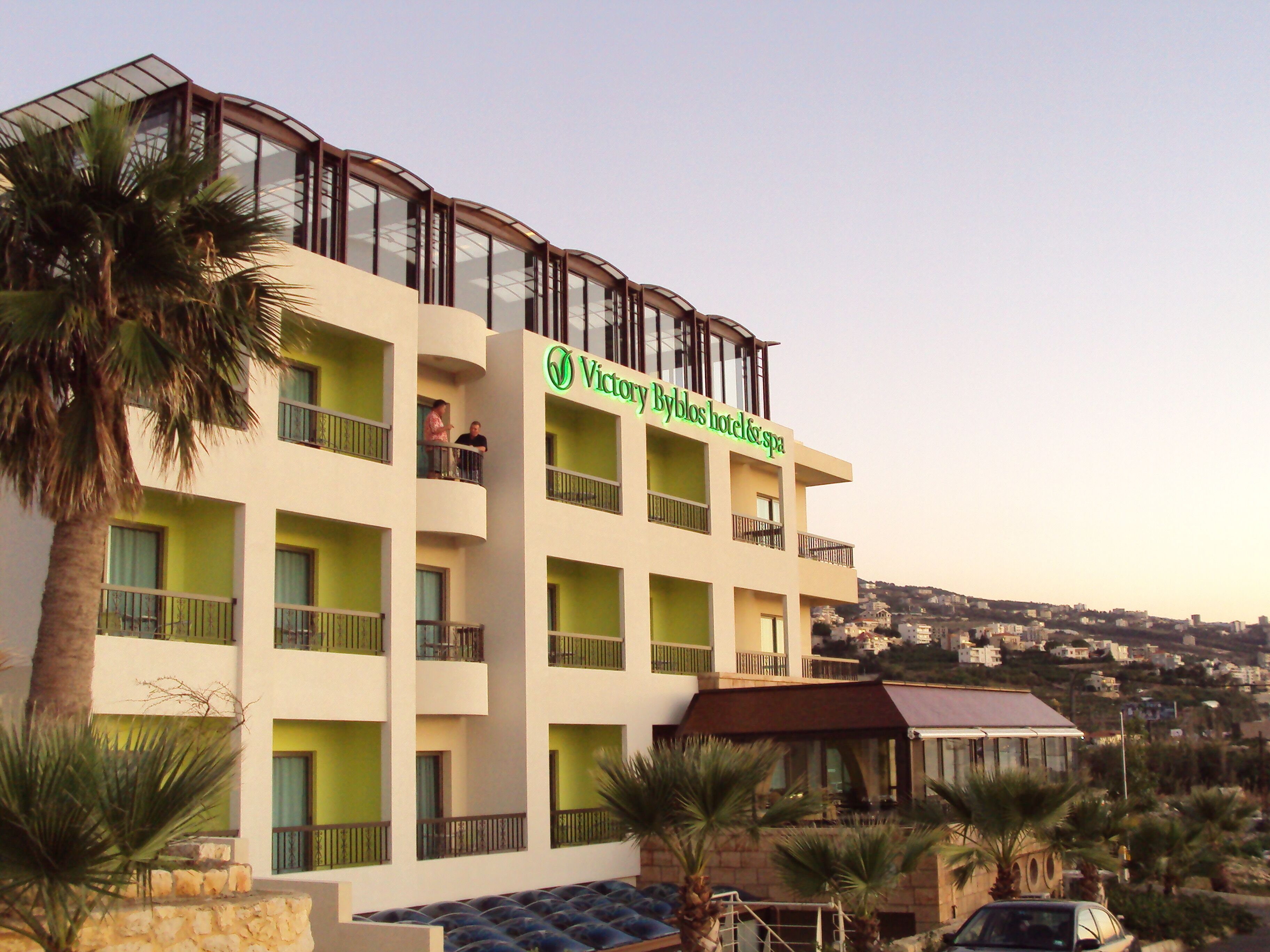 A multi-story hotel with balconies and a sign reading "Victory Byblos hotel & spa".