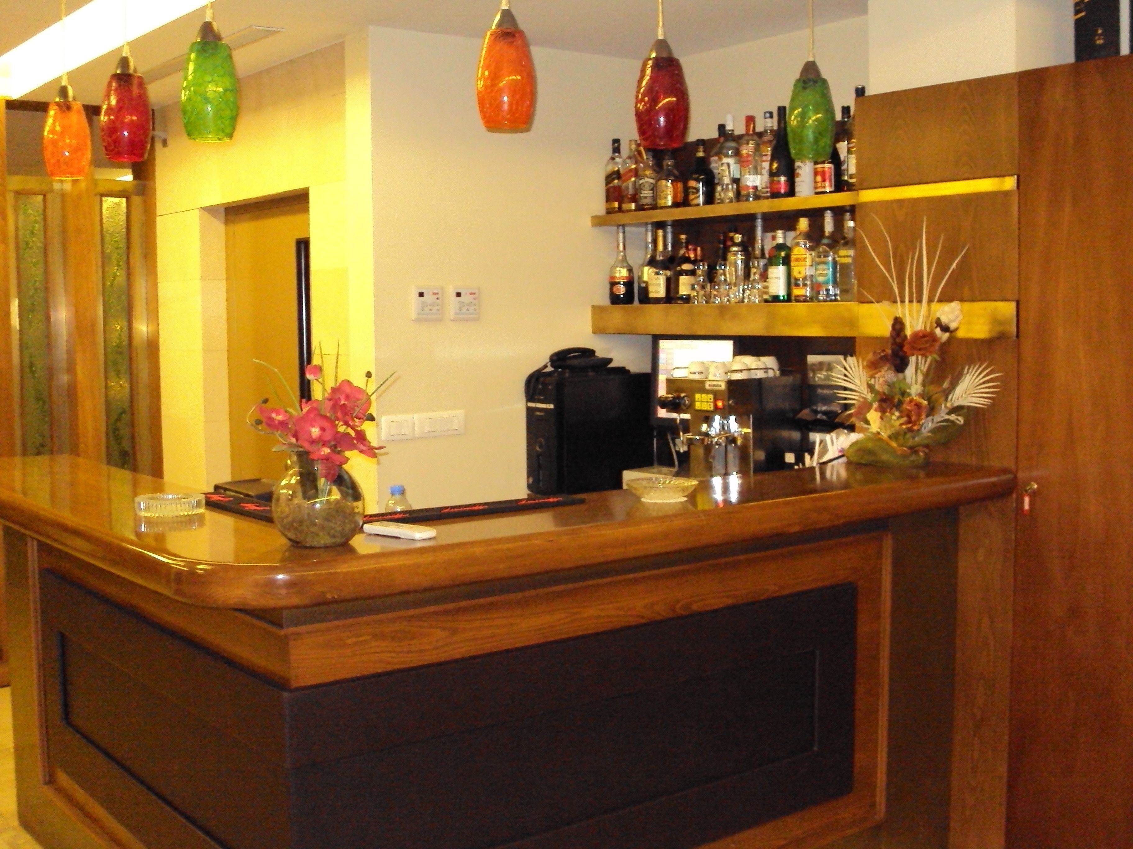 A bar area with wooden counters, a variety of liquor bottles, and hanging pendant lights.