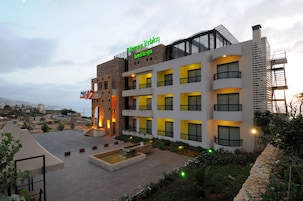 Un hotel con varios balcones, un área de terraza con piscina y vistas a la ciudad.