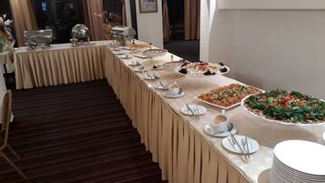 Una mesa de buffet con diversos platos y utensilios, un suelo alfombrado y un espejo que refleja parte de la habitación.