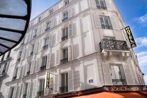 Un hotel con fachada clásica, varios balcones y un cartel de café.