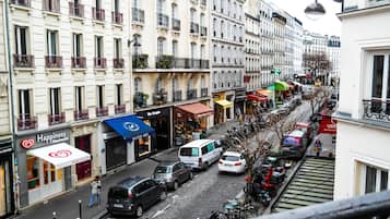Vista de la calle con edificios, tiendas y coches estacionados.