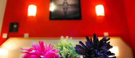 A room with a red wall, a framed picture of the Eiffel Tower, and three flower arrangements.