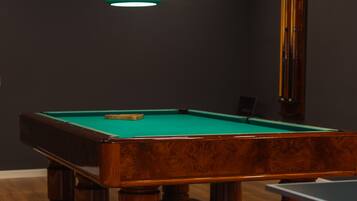 A pool table with a green felt surface, surrounded by wooden legs and a wooden frame.