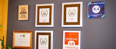 Quadros com prêmios e reconhecimentos em uma parede, incluindo prêmios TripAdvisor e Hotels.com.