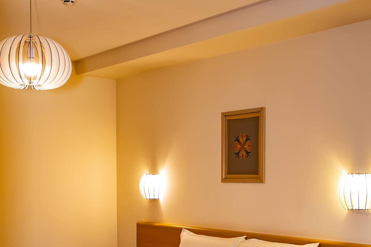 Ett hotellrum med en stor säng, sänglampor, ett nattduksbord och en tavla som hänger på väggen.