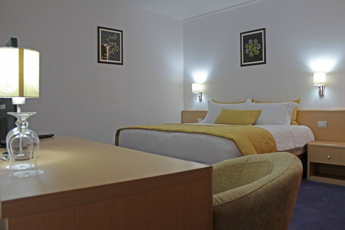 Ett hotellrum med en säng, sängbord, ett skrivbord och en stol.