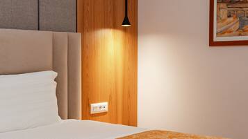 A hotel room with a bed, a wooden panel wall, a painting, and a light fixture.