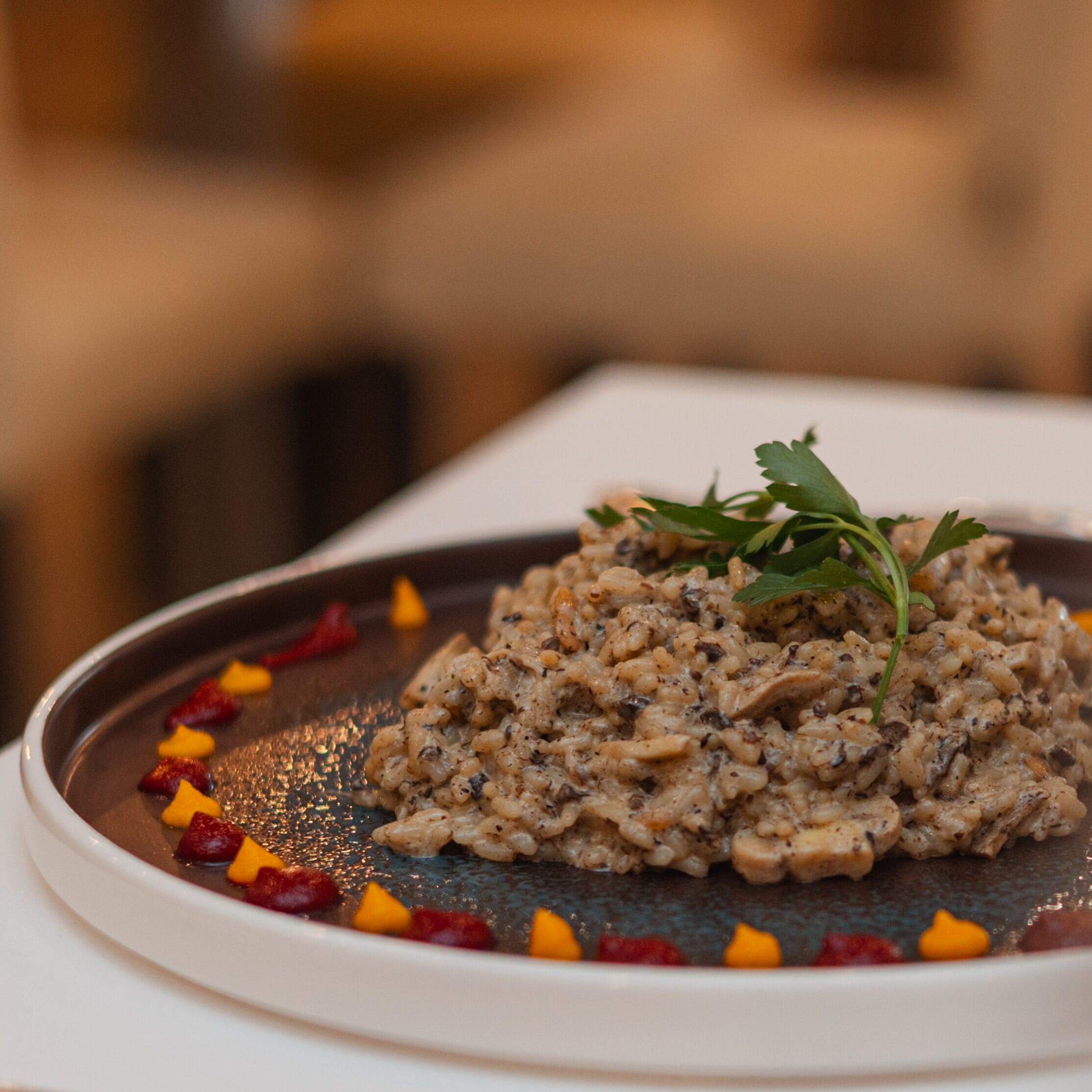 A plate of risotto with mushrooms and garnished with parsley, served on a white plate with a decorative border.